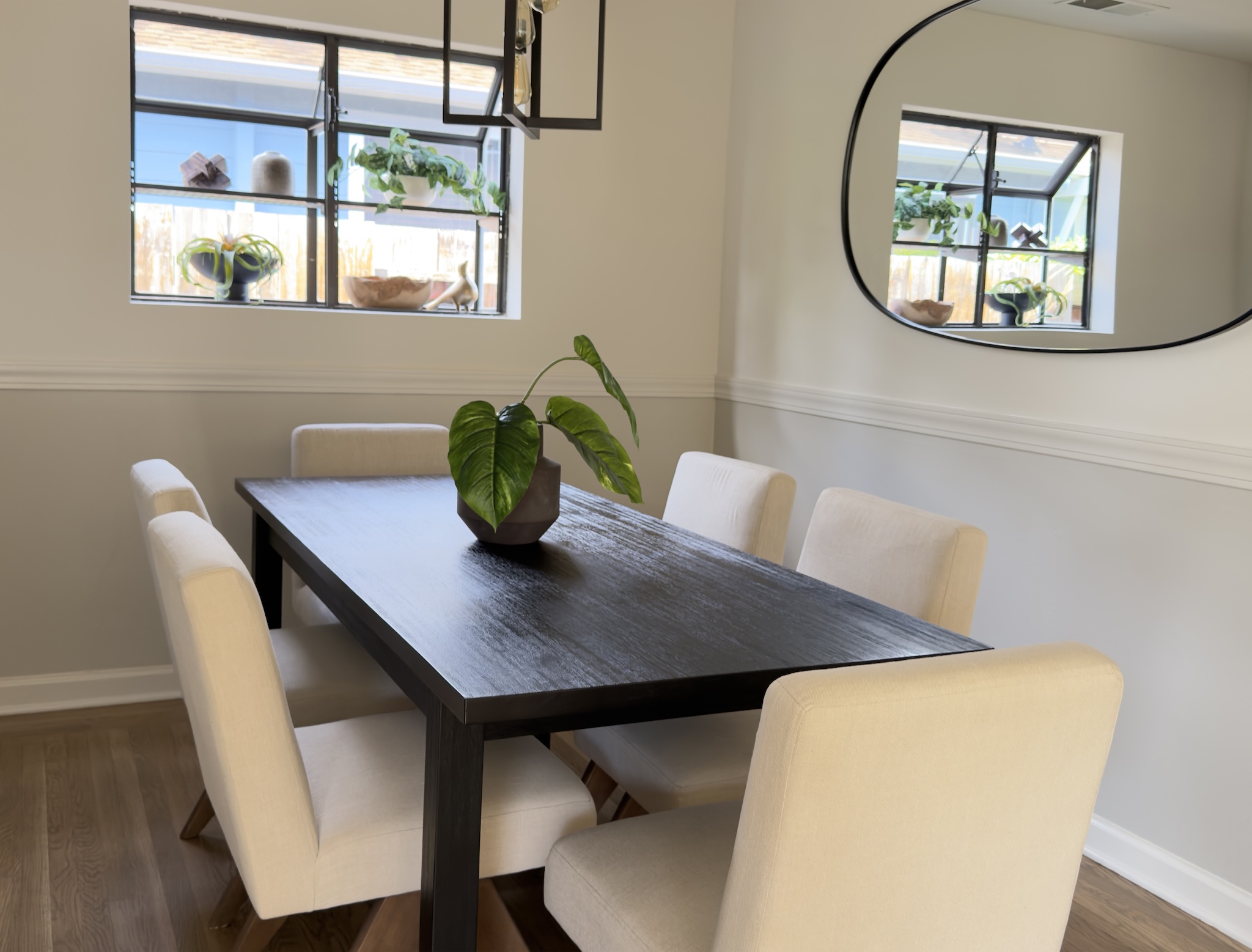 Dining room with dark wood table, cream chairs and oval mirror