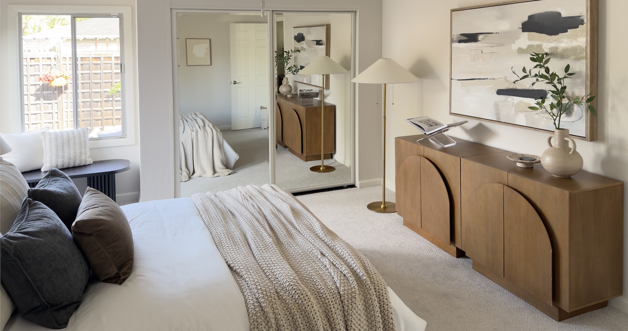 Primary bedroom with wood credenza and floor lamp