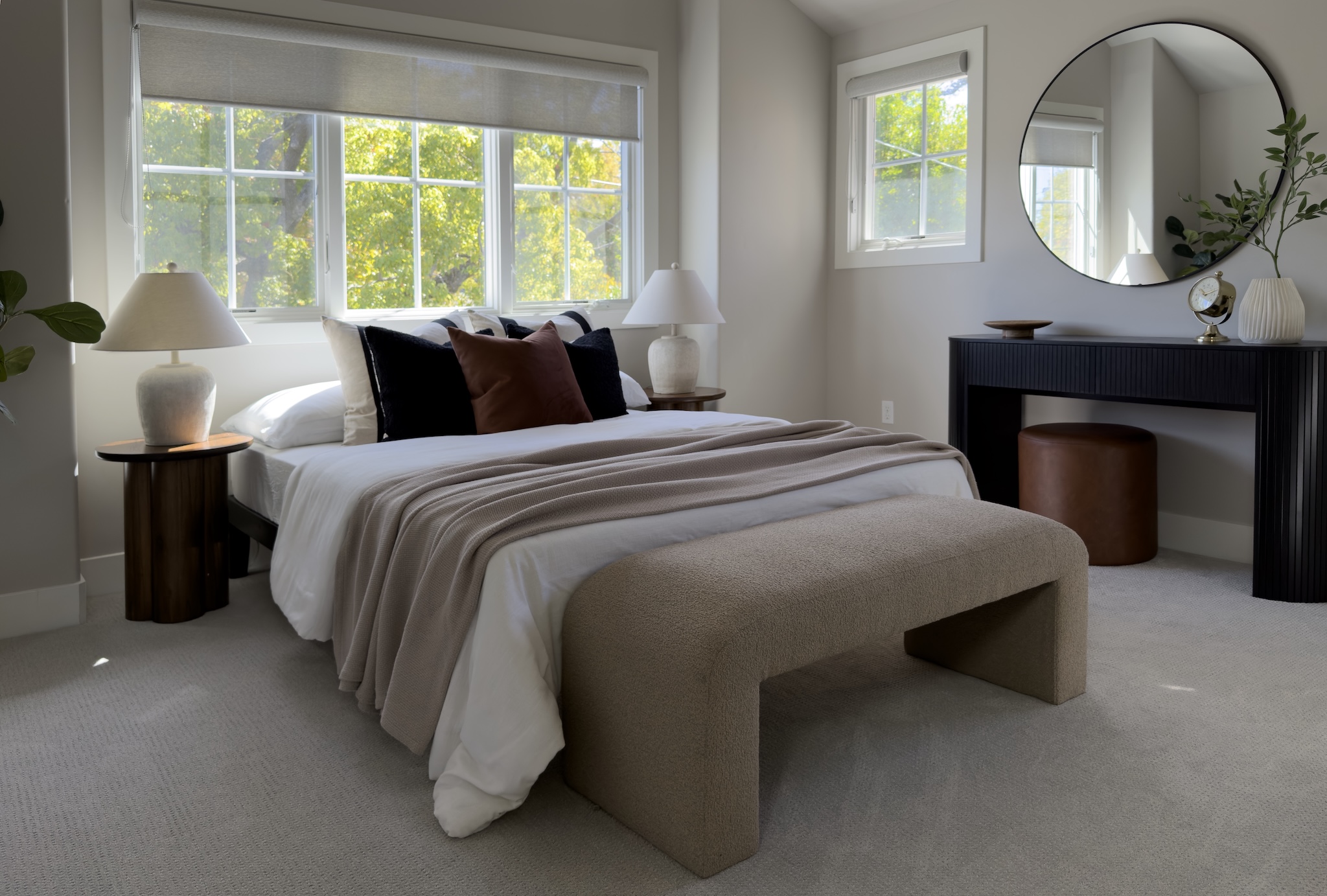 Bedroom with upholstered bench and round mirror