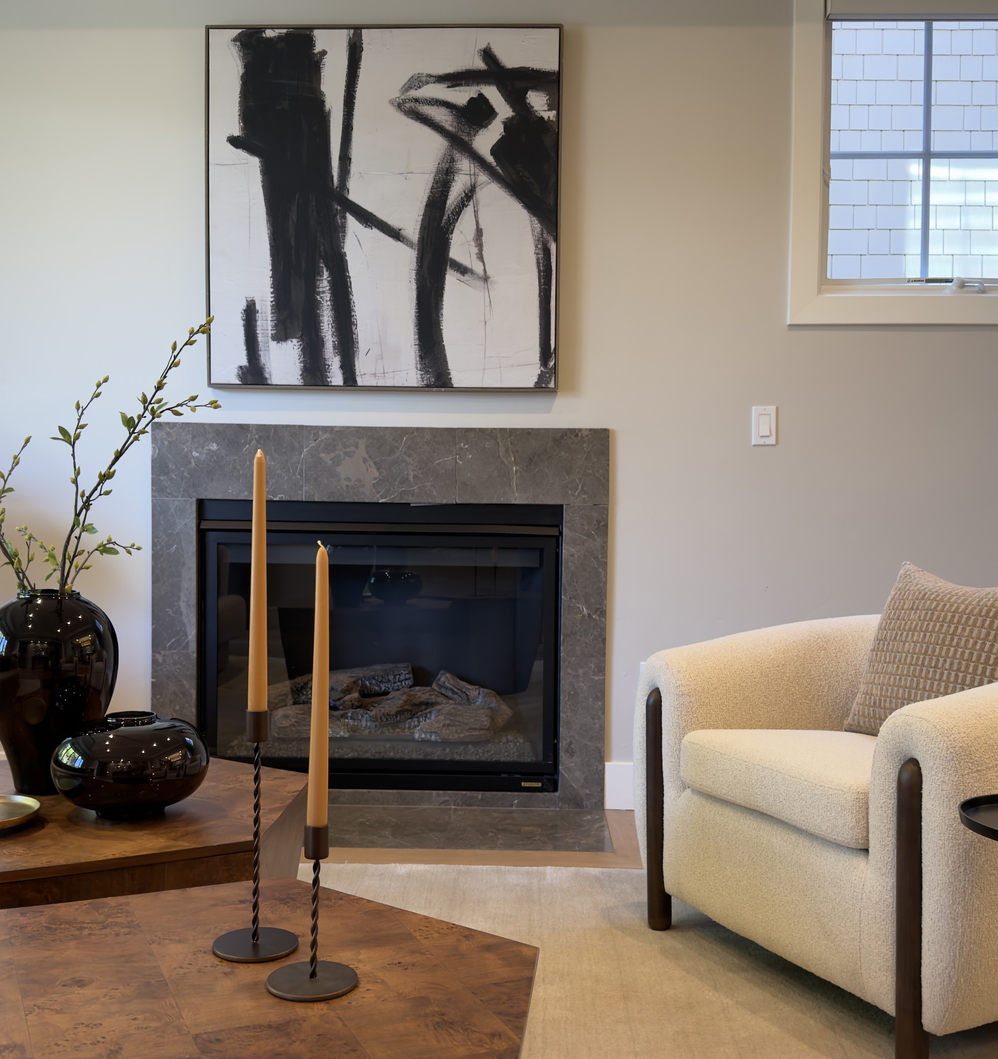 Living room fireplace with abstract artwork and bouclé armchair