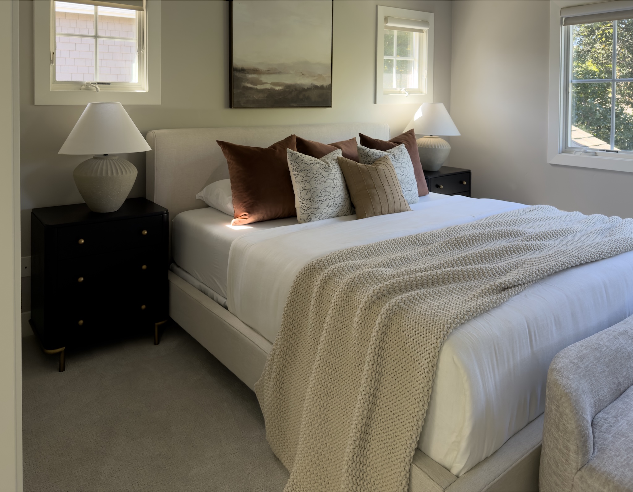 Primary bedroom with layered pillows and knit throw