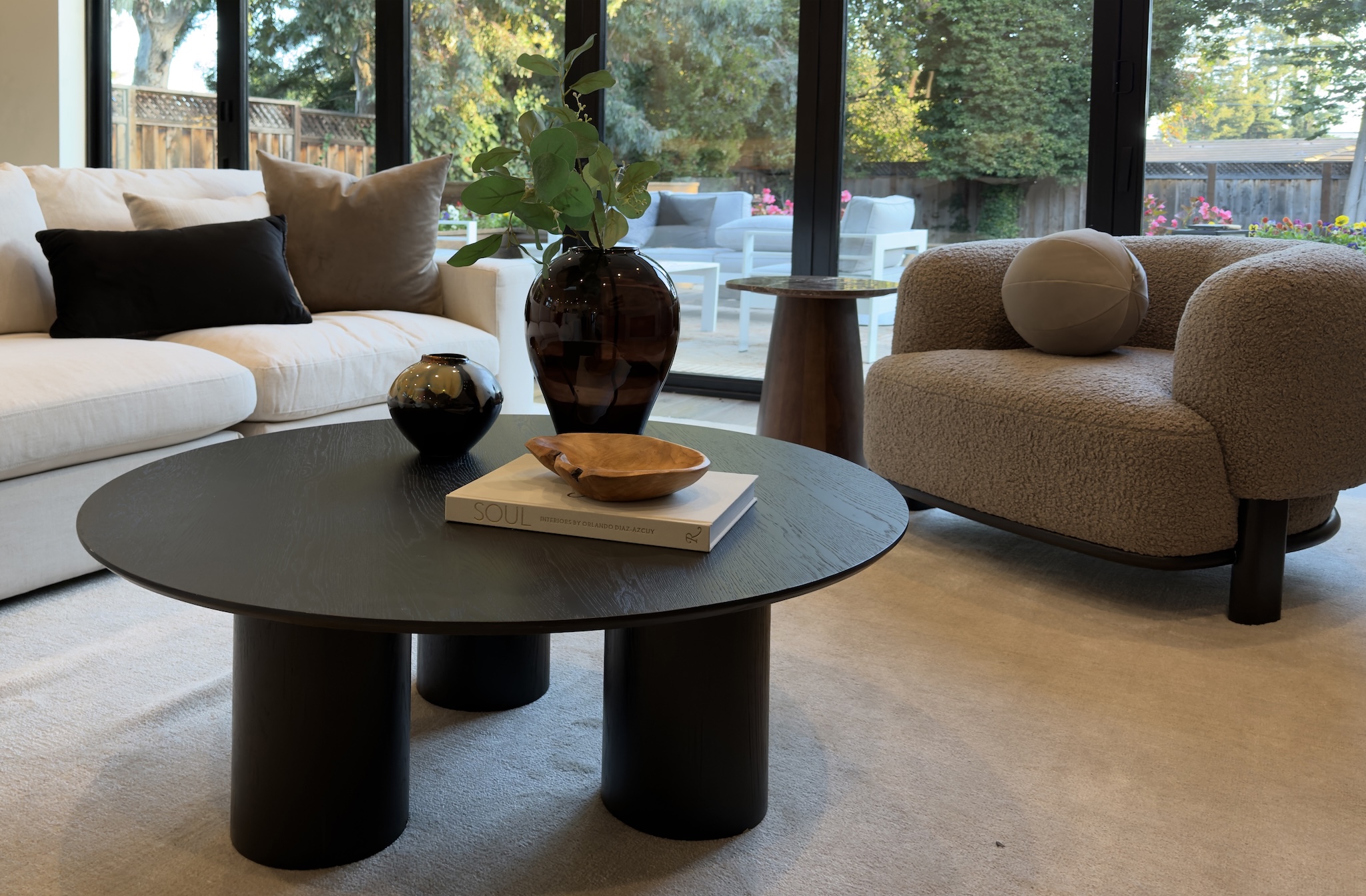 Family room with round black coffee table and bouclé armchair