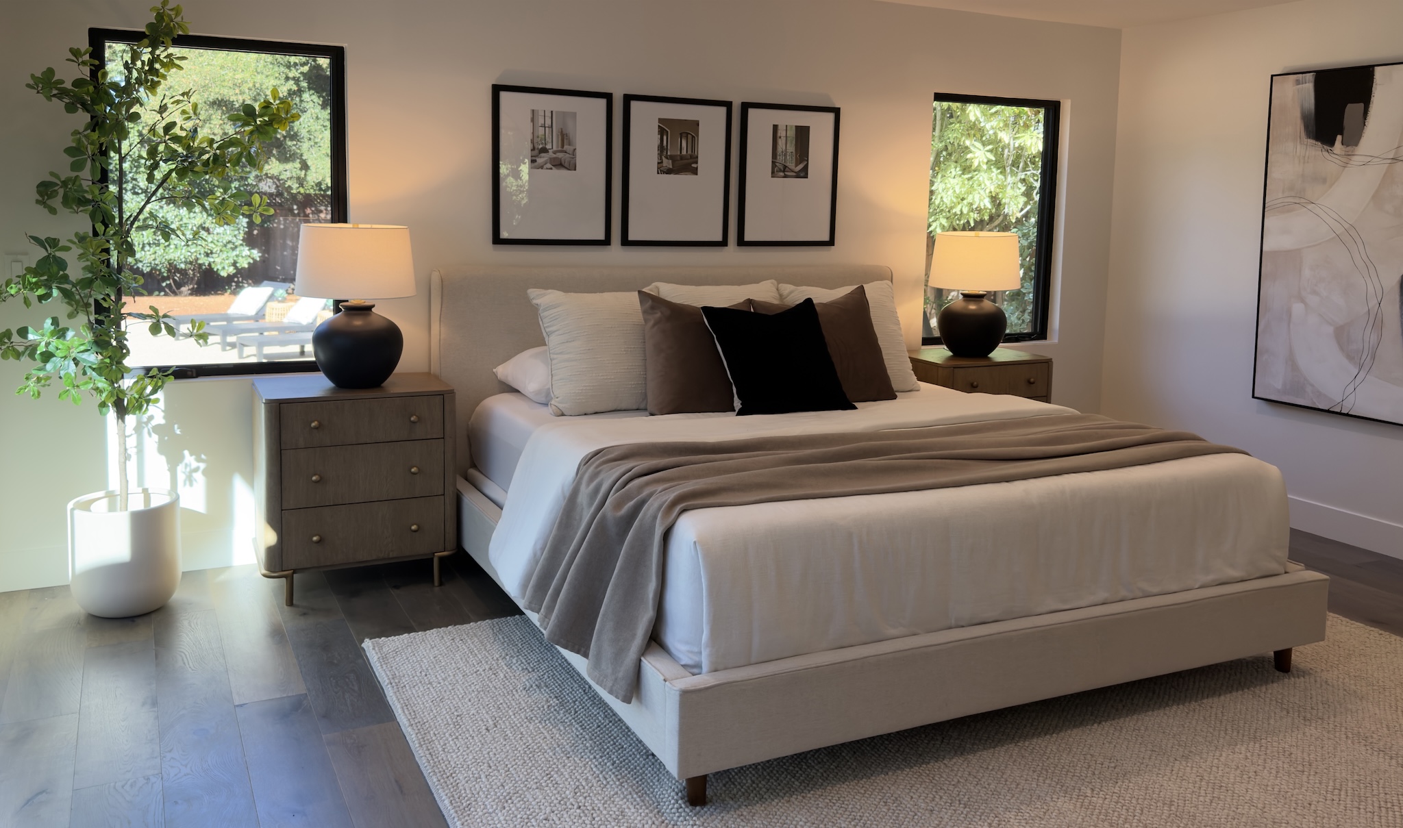 Staged primary bedroom with upholstered bed and framed prints